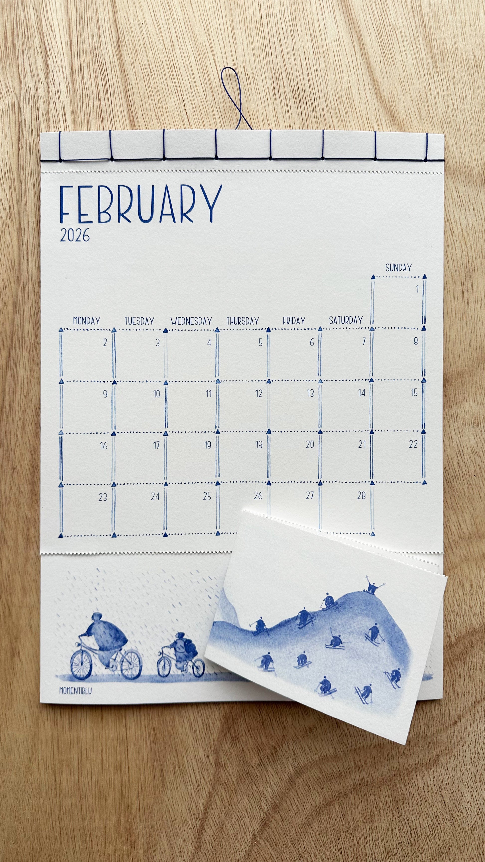 February 2026 calendar with watercolor designs on a wooden surface